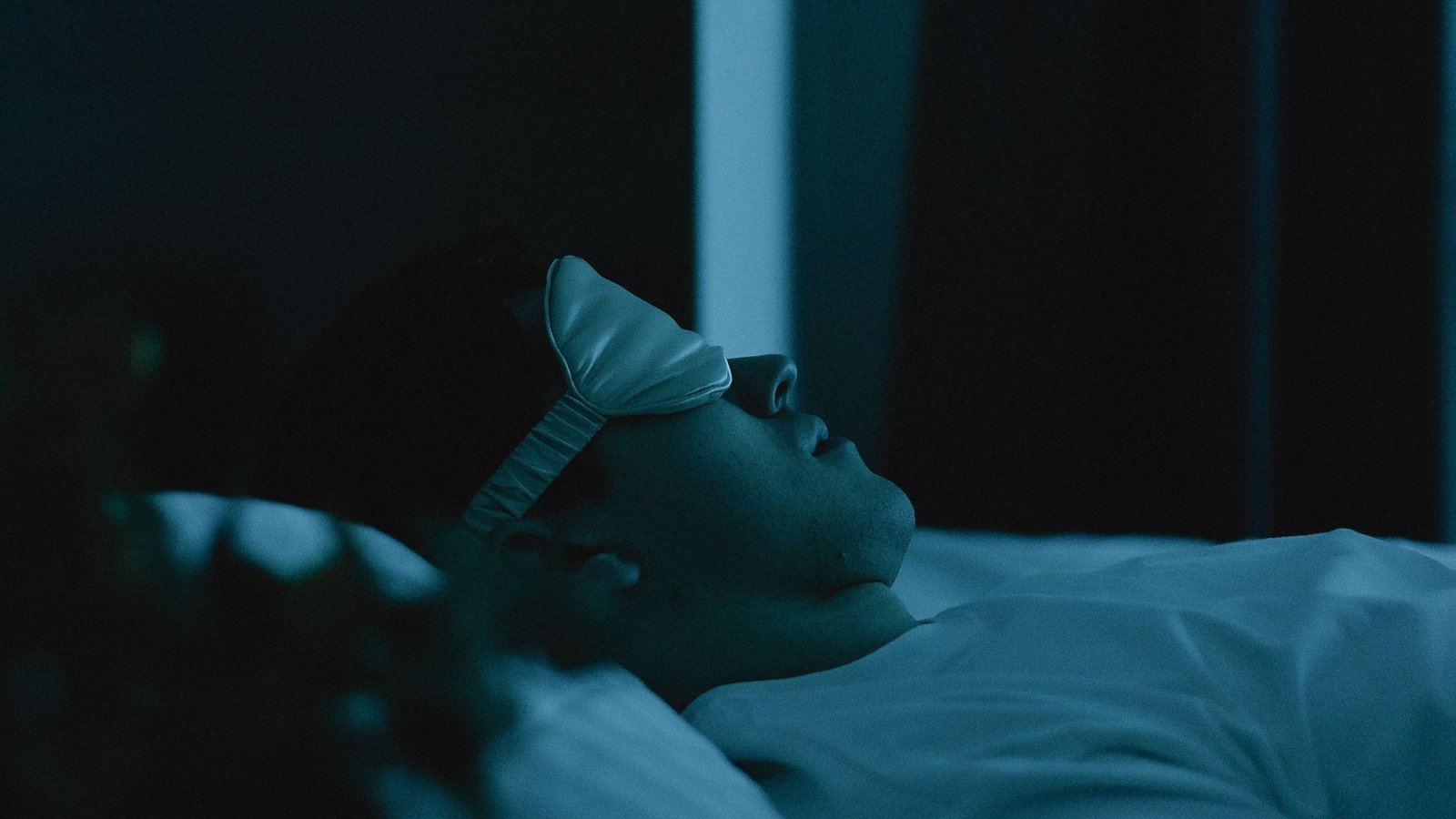 A man resting in a dark bedroom — poor sleep is one of the fastest ways to suppress testosterone production