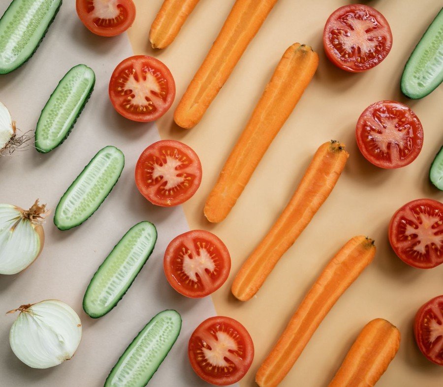Top view of fresh sliced vegetables including carrots, cucumbers, onions, and tomatoes