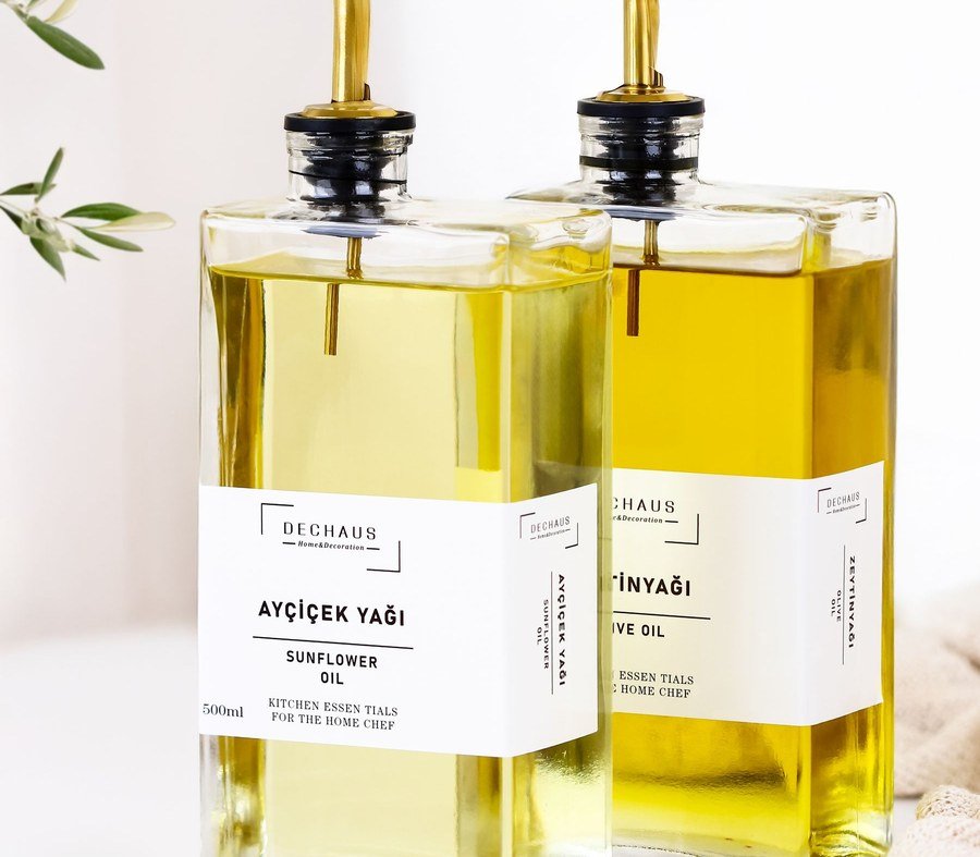 Glass bottles of olive and seed oils arranged with olives on a table