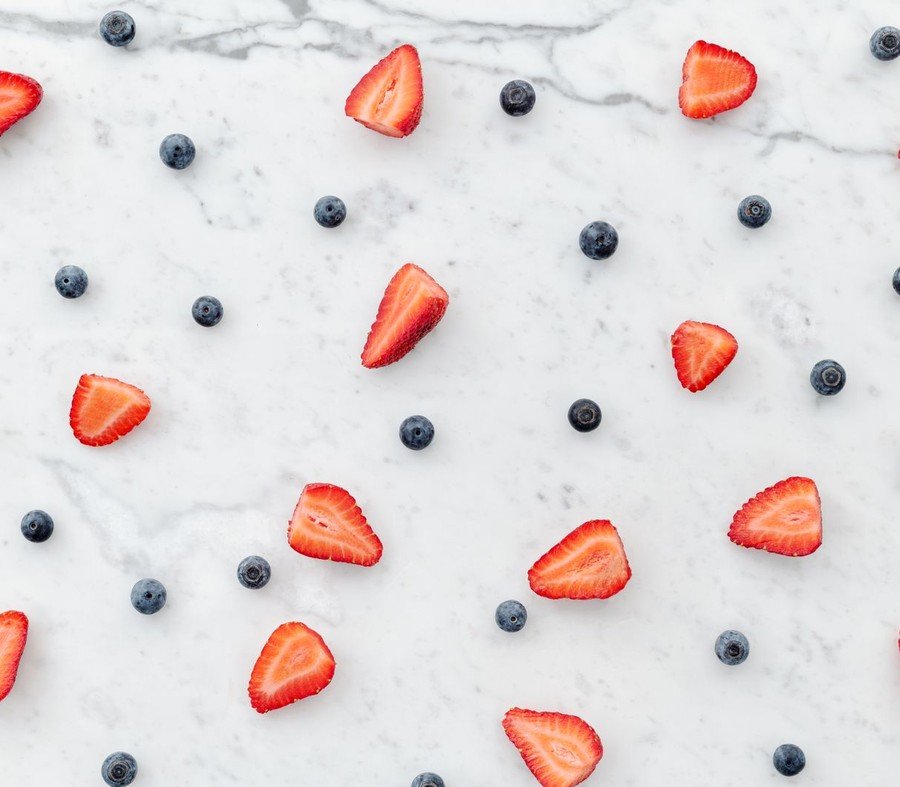 Fresh strawberries and blueberries on a marble surface